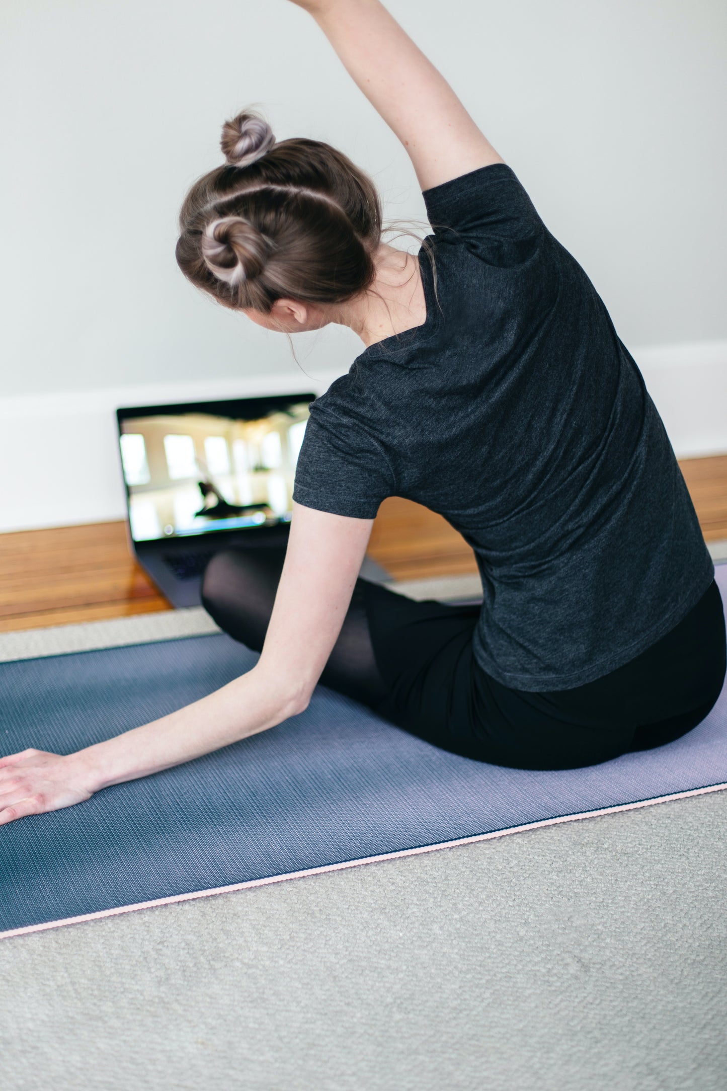 Young woman practices yoga on her mat at home.