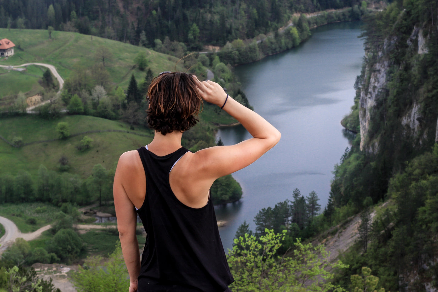 Traveling woman hiking in nature views countryside from high vantage point.