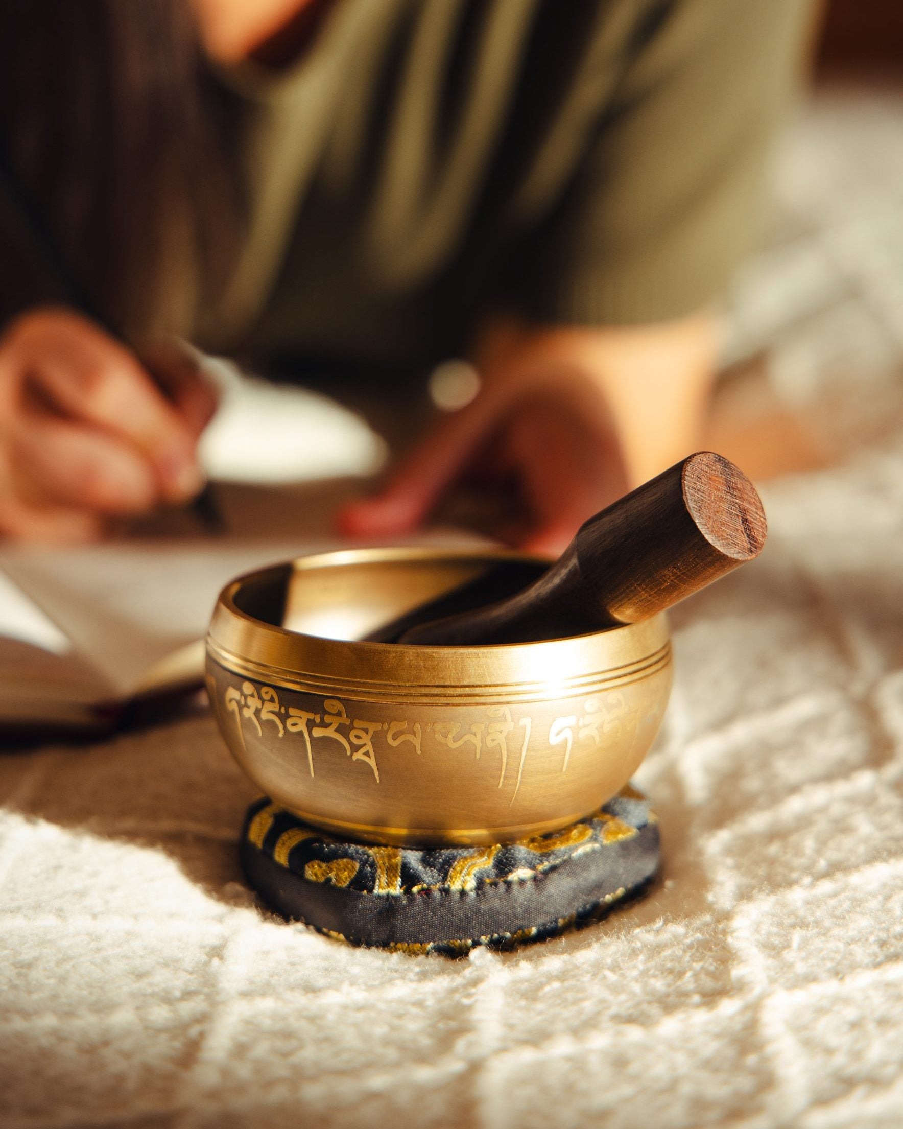 A warm home table with a singing bowl, cushion, and striker