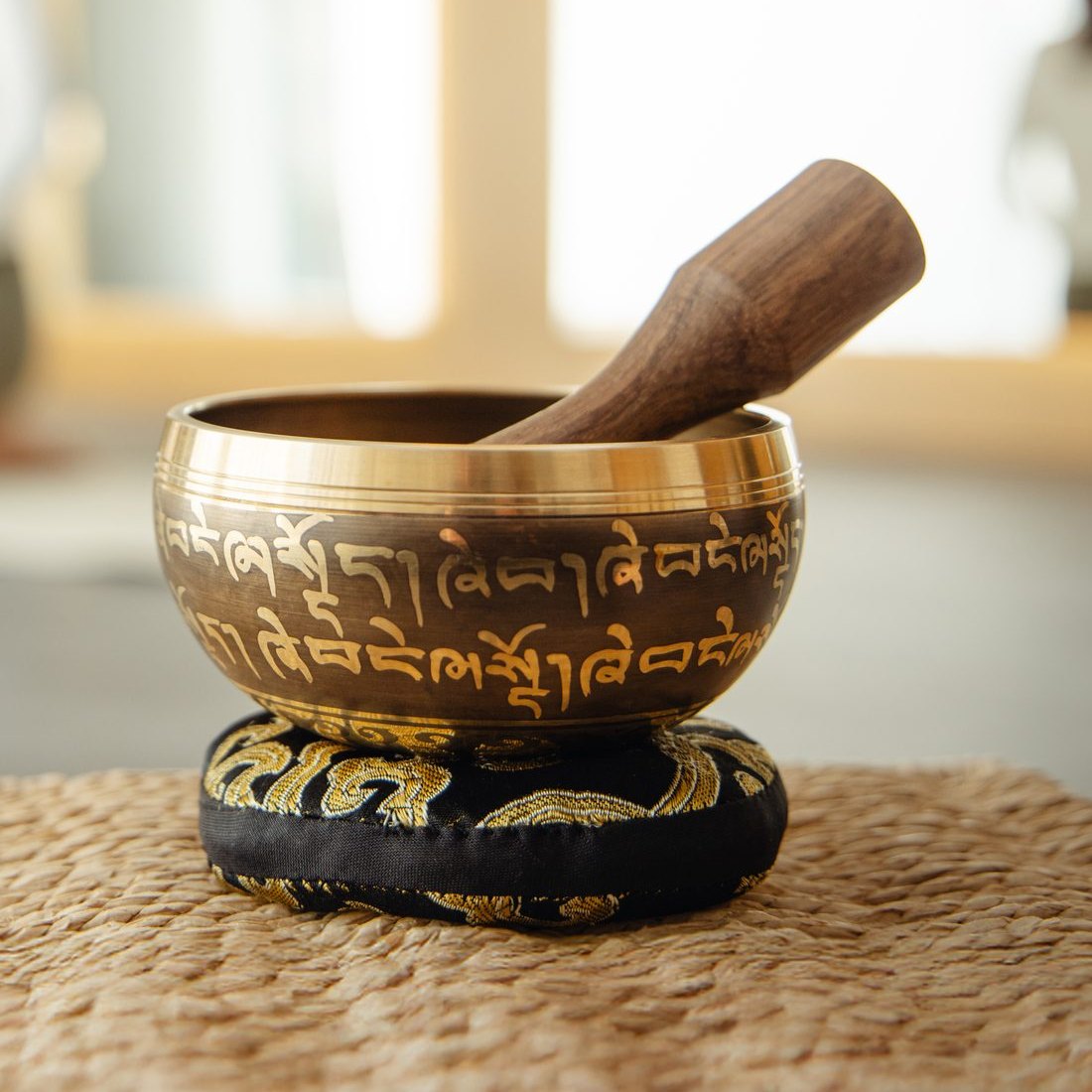 A singing bowl resting on its cushion with the striker laid inside it, as the sound fades