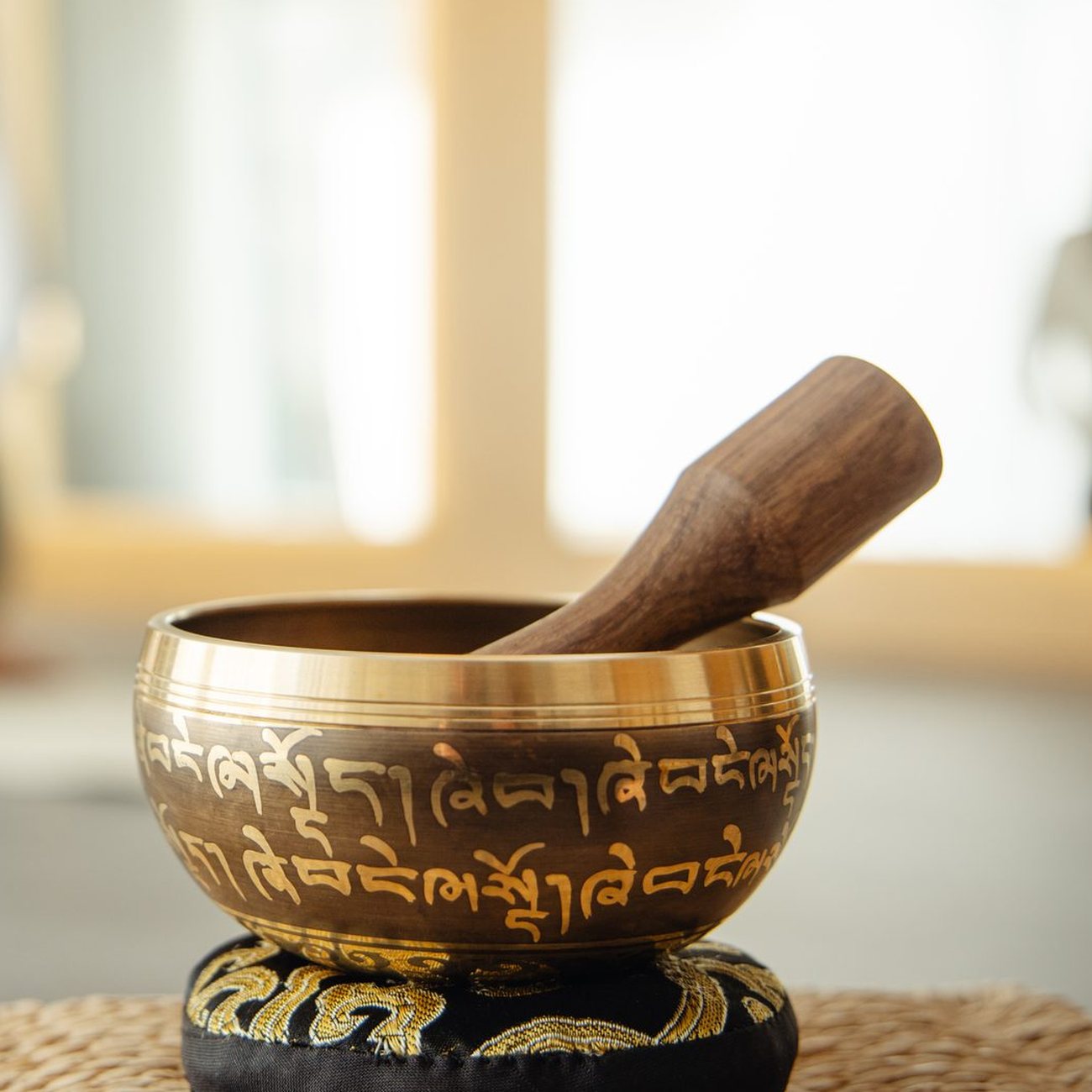 A singing bowl resting on its cushion with the striker laid inside it, as the sound fades