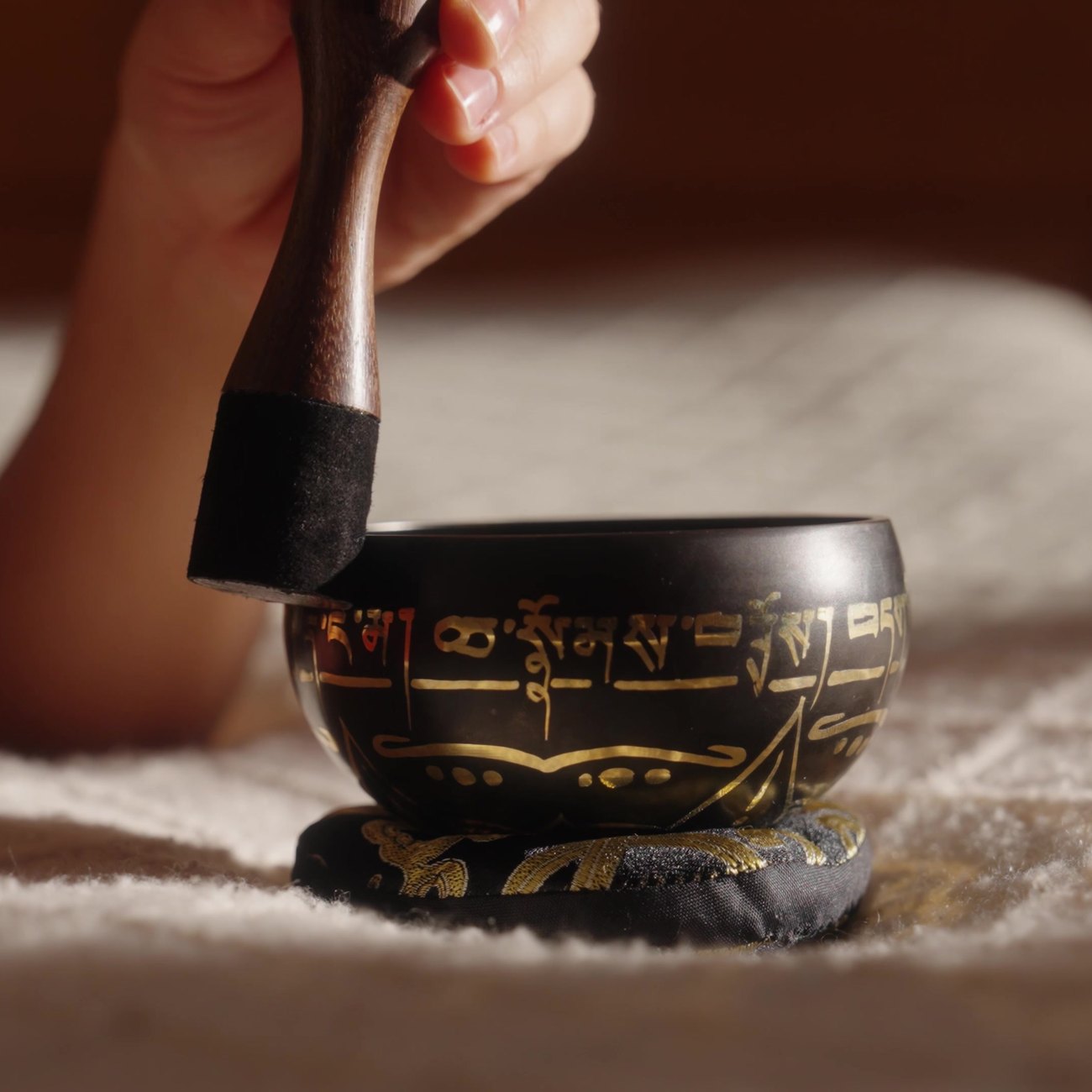 A hand holding the striker upright against the outside of the bowl's rim