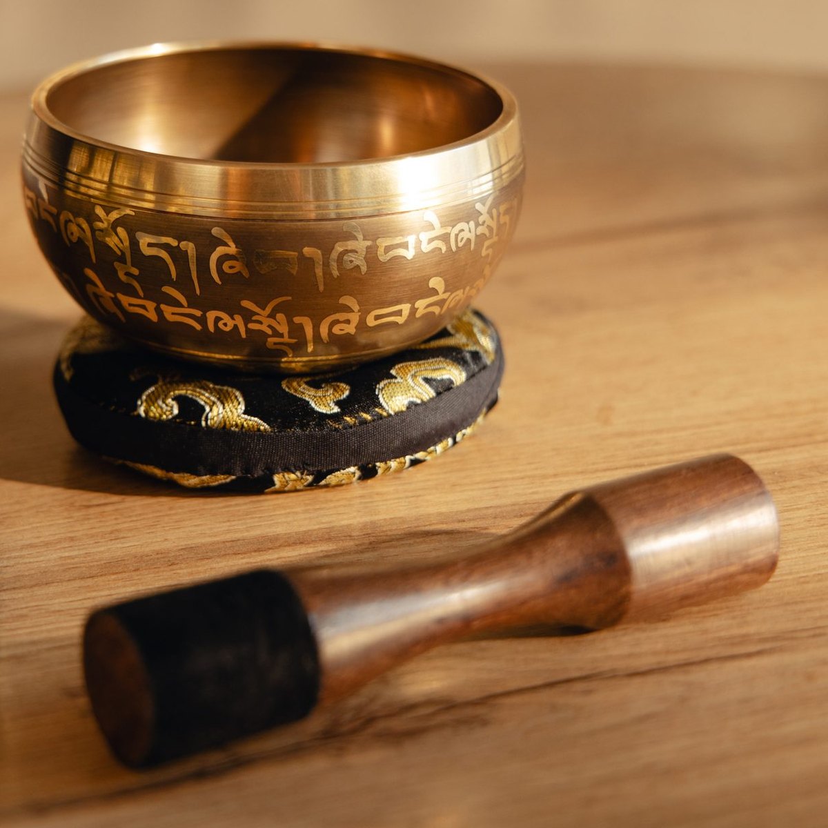 A singing bowl resting on its cushion, the striker laid beside it as the sound fades