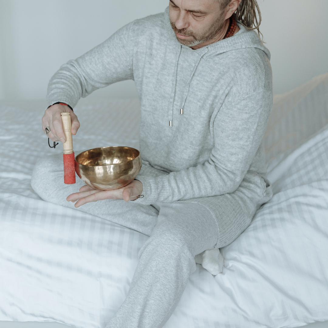 Man in his Pajamas playing singing bowl in bed