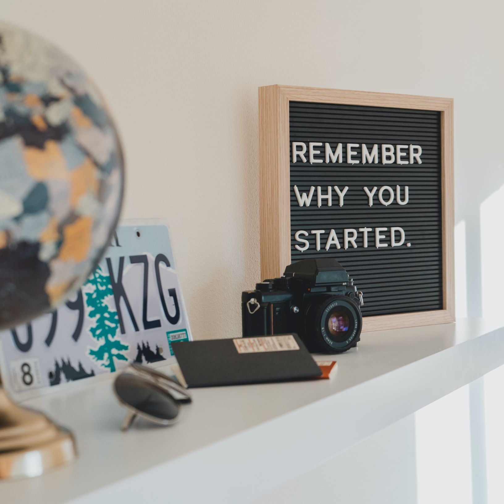 A camera, license plate, sunglasses, and other objects adorn a mantle.