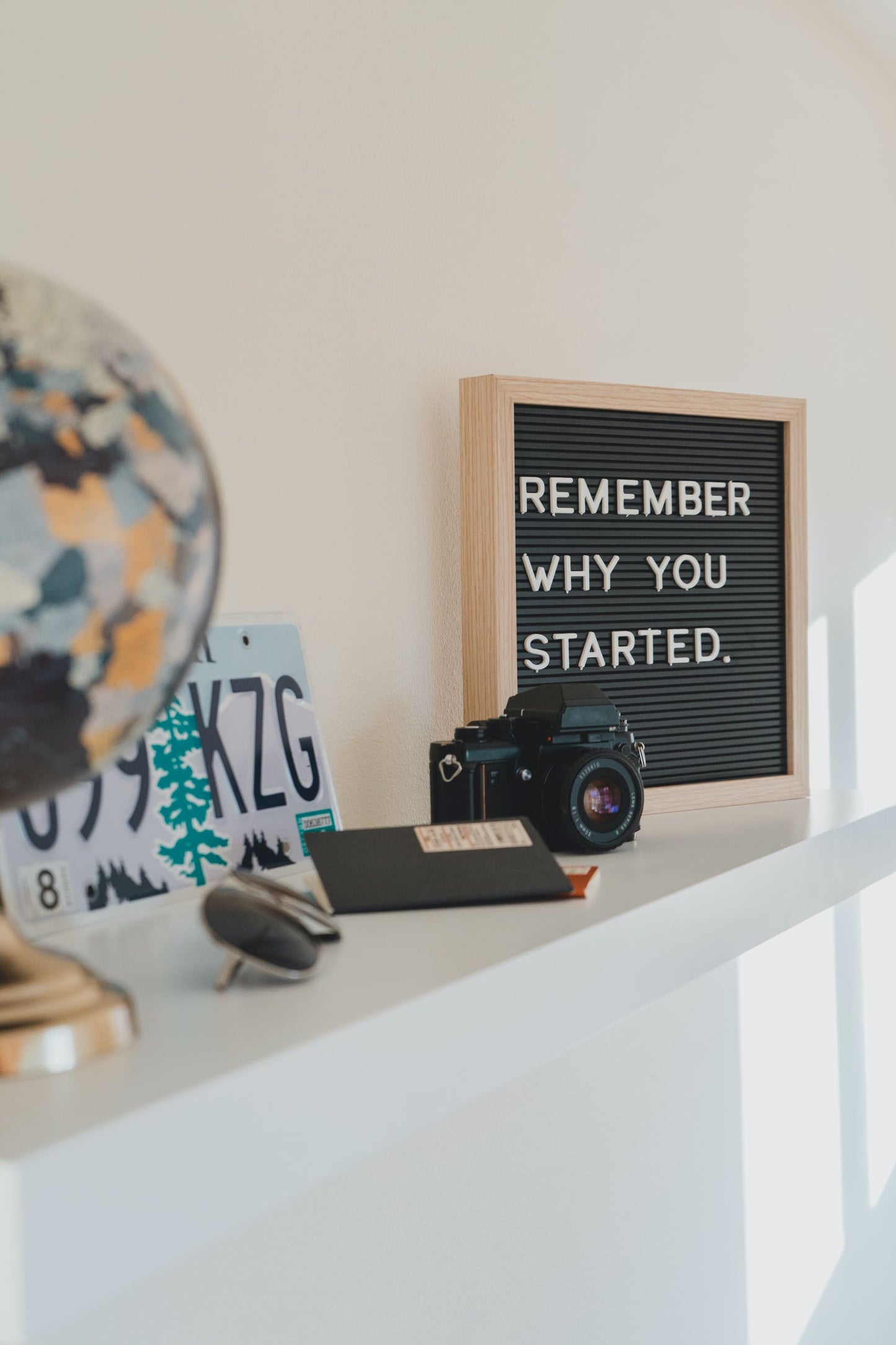 A camera, license plate, sunglasses, and other objects adorn a mantle.