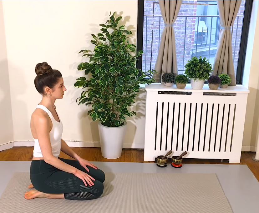 A young woman kneels on her yoga mat as two Silent Mind singing bowls sit nearby.