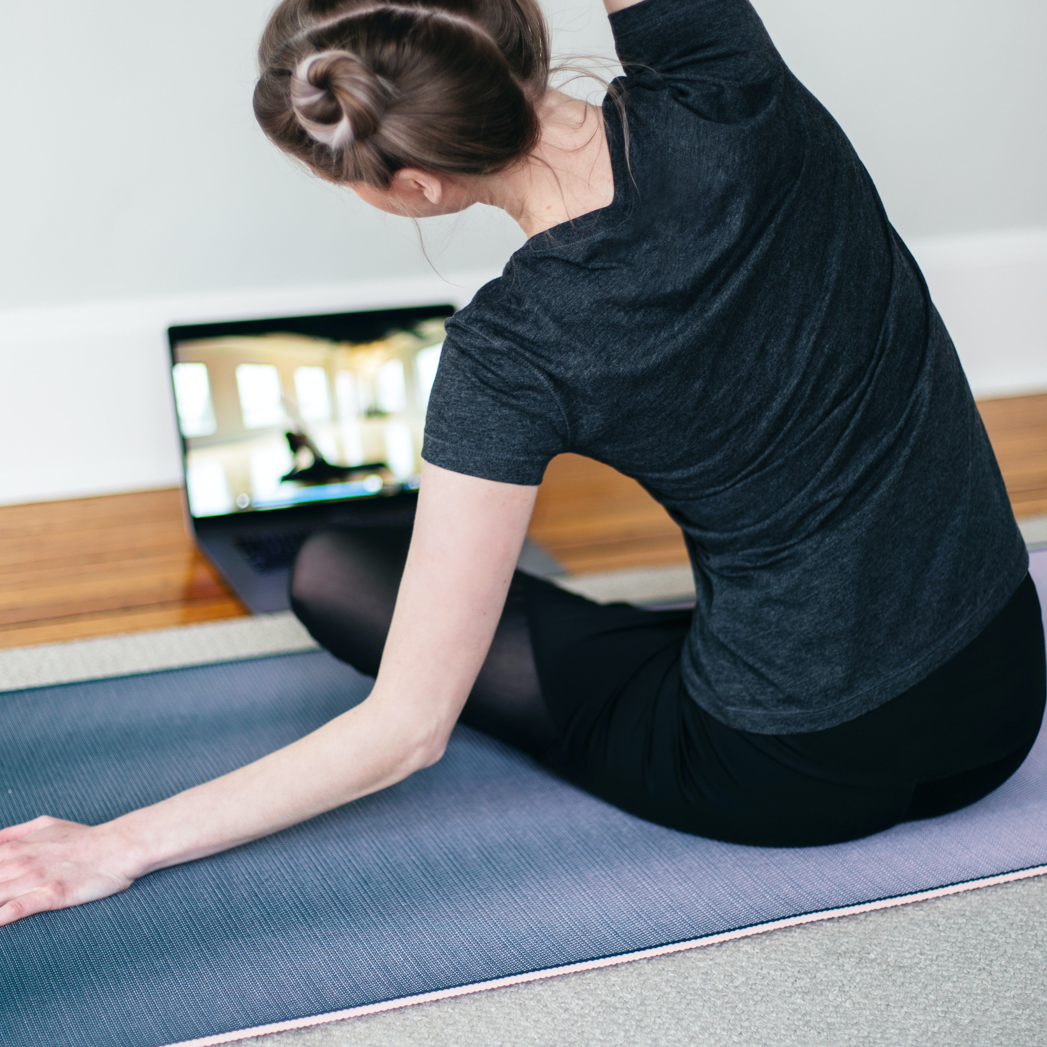 Young woman practices yoga on her mat at home. 