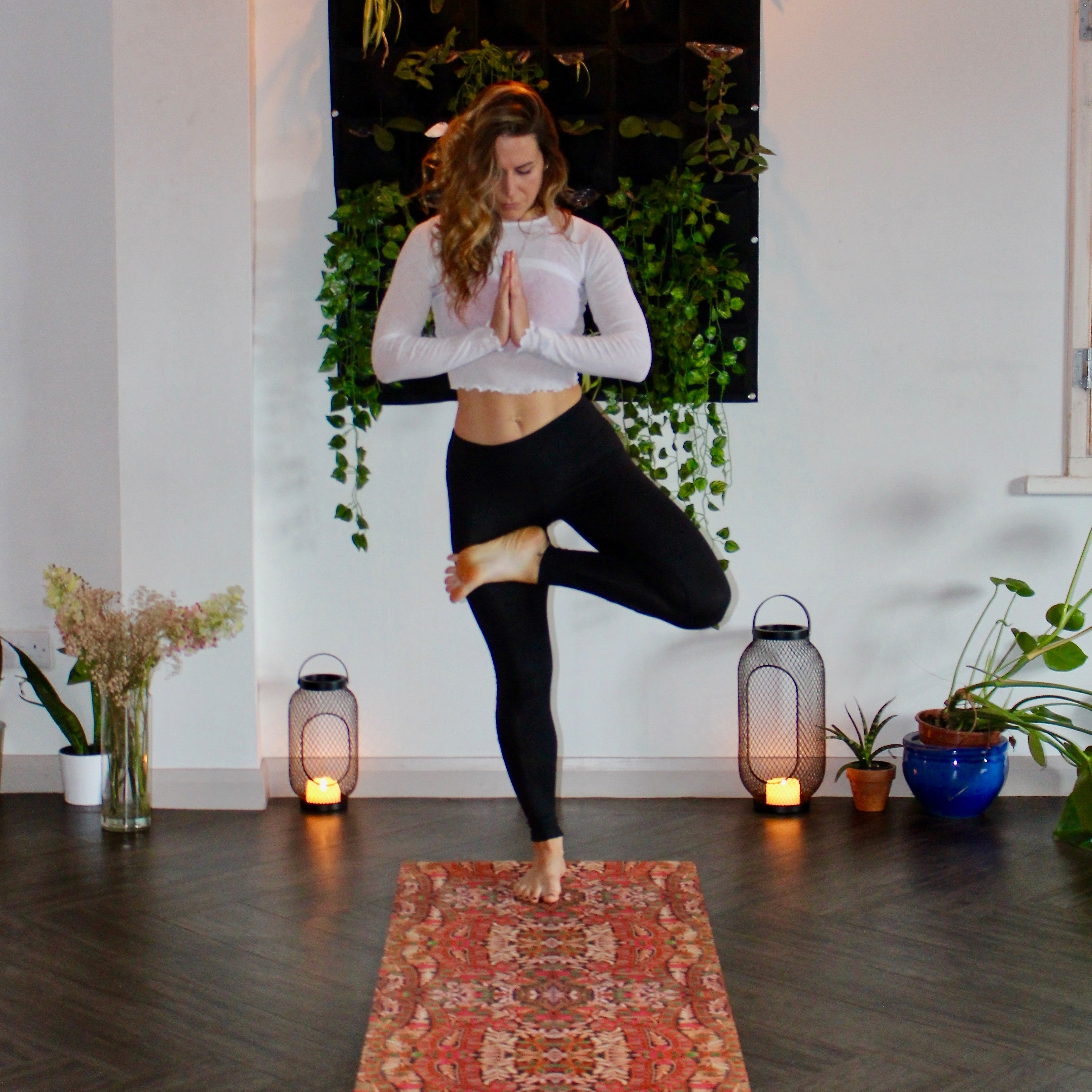 A woman stands in tree pose during her home yoga practice.