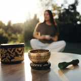 The Golden Harmony singing bowl on its cushion on a garden table in warm evening light