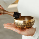 Golden Serenity singing bowl held in the hand, striker ready