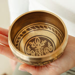 Golden Serenity singing bowl held in the hand, striker ready