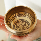 Golden Serenity singing bowl held in the hand, striker ready
