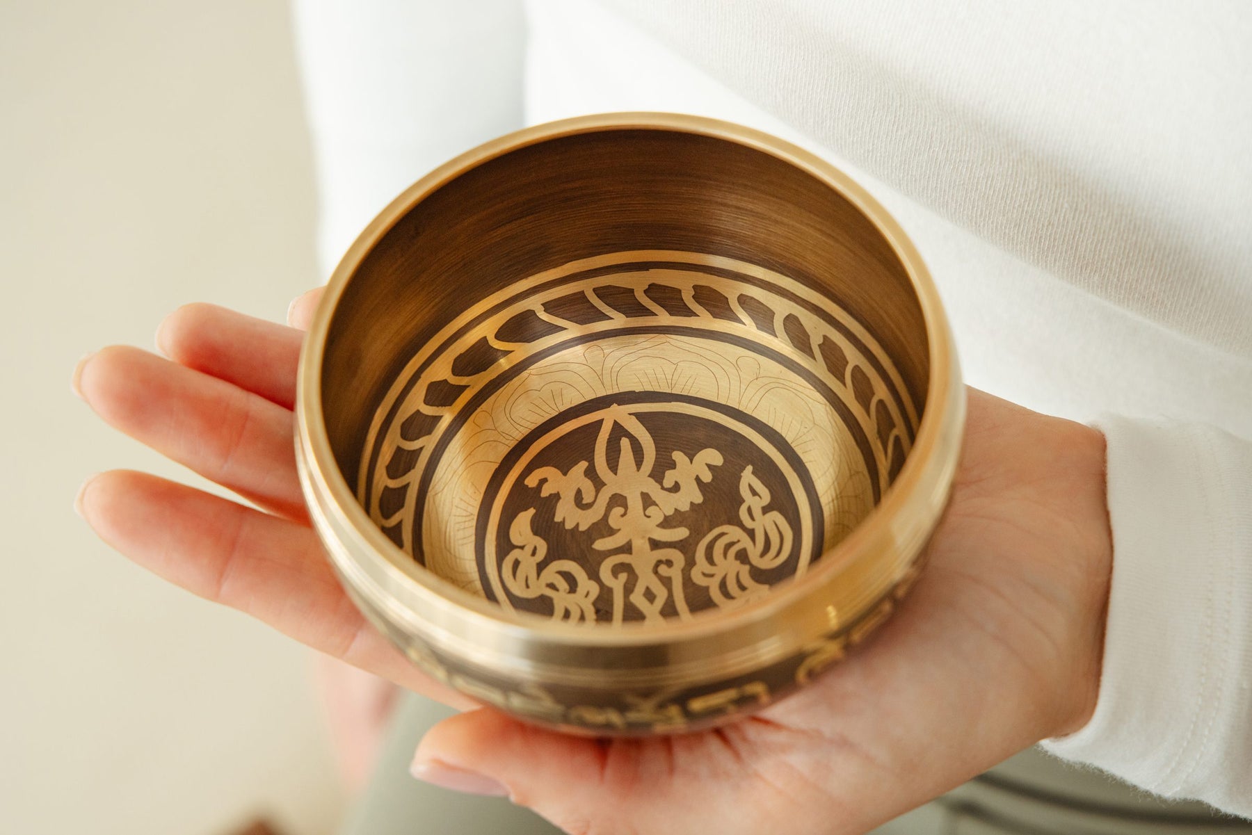 Singing bowl with cushion and striker on a warm wood table