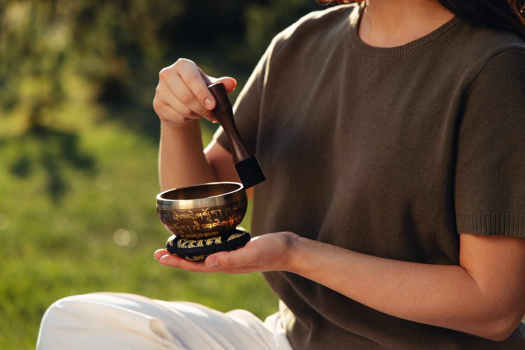A compact singing bowl on a warm home table with a hand for scale